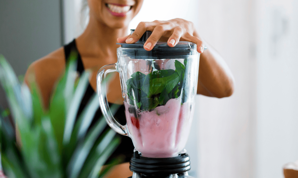 Blender on counter and lady making a smoothie