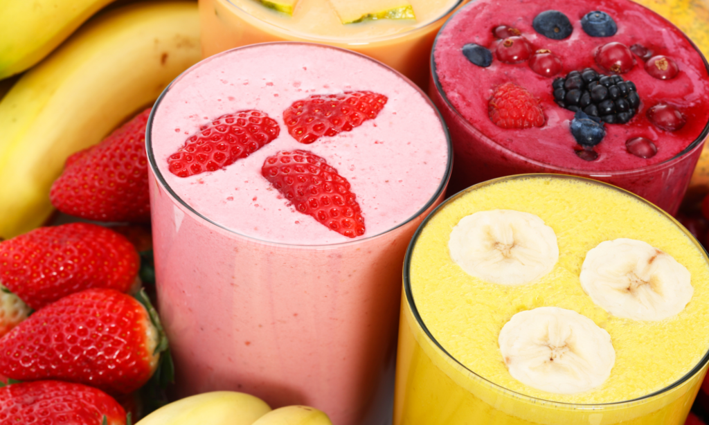 close up shot of 4 smoothies with fruit on top