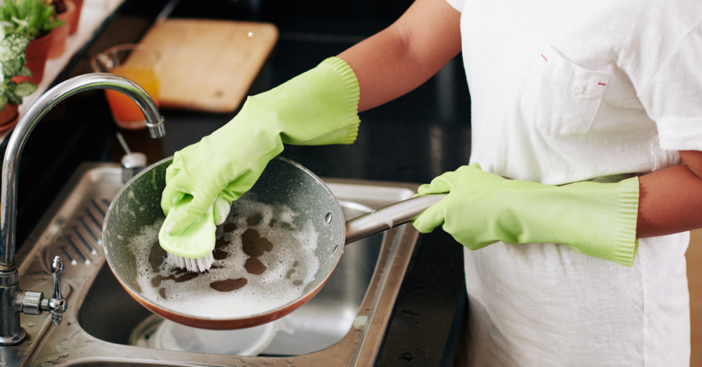 A woman cleaning a pot in a kitchen sink